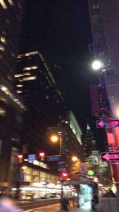 a city street at night with people walking on the sidewalk