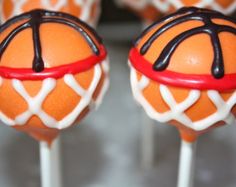 two orange cake pops with chocolate drizzle on them, sitting on top of each other