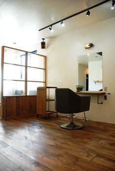 an empty room with wooden flooring and a chair in front of a mirror on the wall