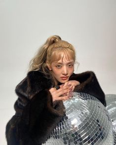 a woman in a fur coat holding a disco ball