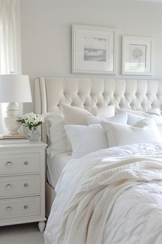 a bed with white linens and pillows in a small room next to two pictures on the wall