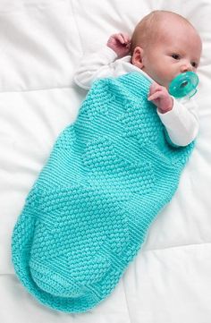 a baby laying on top of a bed with a pacifier in its mouth