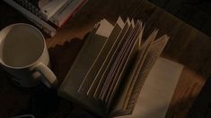 a stack of books sitting on top of a wooden table next to a cup of coffee