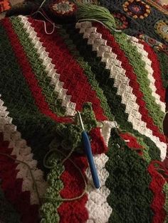 a crocheted afghan is laying on the floor next to a pair of scissors