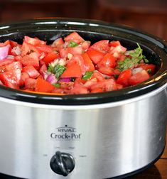 a crock pot filled with chopped vegetables on top of a wooden table