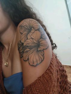 a woman's arm with a flower tattoo on the left side of her shoulder