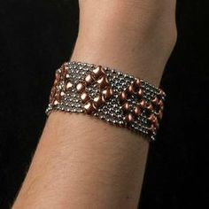 a woman's hand wearing a bracelet with brown and silver beads on it,