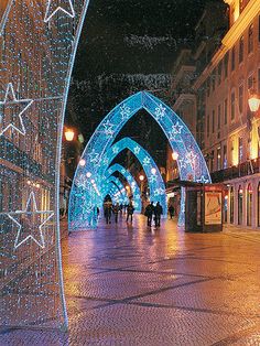 an archway decorated with christmas lights in the middle of a street