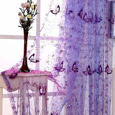 purple sheer curtains with butterflies on them and a vase full of flowers in front of the window