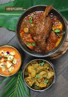 three bowls filled with different types of food on top of a wooden table next to green leaves