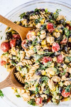 a bowl filled with pasta salad and wooden spoons