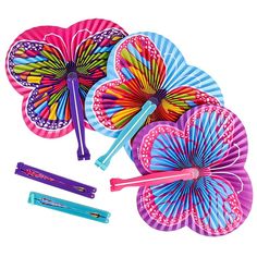 several colorful paper fan shaped like flowers and two are laying next to each other on a white background