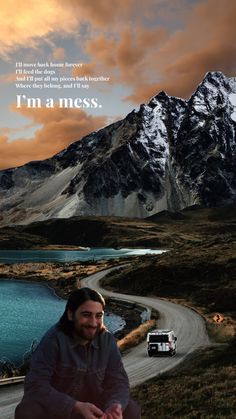 a man sitting on the side of a road next to a mountain