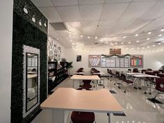 an empty classroom with desks and chairs in front of the chalkboard wall that is decorated with christmas lights