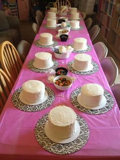 a long table with several cakes on it and plates in front of the table are empty