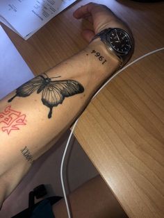 a person's arm with a butterfly tattoo on it and a watch sitting on the wrist