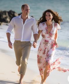 a man and woman are walking on the beach holding hands as they run towards the water