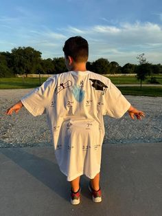 a young boy is standing in the middle of a parking lot with his arms spread out