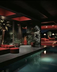 a living room filled with red couches next to a swimming pool and palm trees