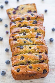 slices of blueberry bread sitting on top of a wooden table next to fresh blueberries