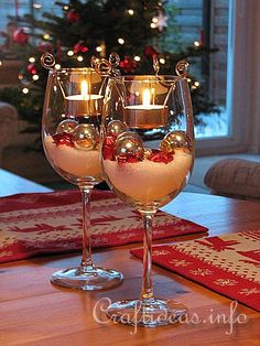 two wine glasses filled with liquid sitting on top of a table next to a christmas tree