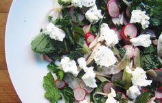 a salad with radishes, onions and feta cheese on it sitting on a white plate