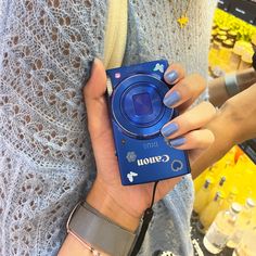 a woman is holding a camera in her left hand while she's wearing bracelets