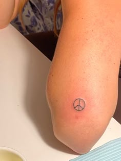 a woman with a small peace sign tattoo on her arm