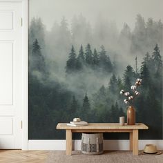 a table with vases on it in front of a forest wall mural