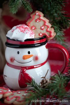 a snowman mug with a cookie in the shape of a christmas tree