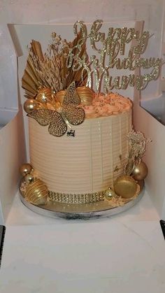 a white cake with gold decorations in a box