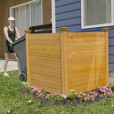 a wooden fence in front of a house with flowers growing on the ground next to it