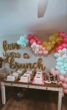 a table topped with lots of cake and balloons next to a sign that says love you a brunch