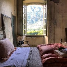 a bedroom with a bed, chair and window overlooking the mountains is pictured in this image