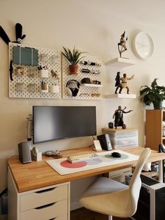 a desk with a computer monitor, keyboard and various figurines on the wall