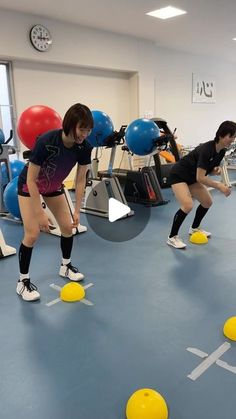 three people in a gym doing exercises with exercise balls on the floor, while one woman watches