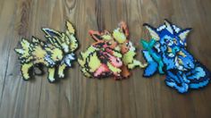 three pixelated pokemon brooches sitting on top of a wooden floor