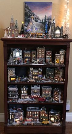 a wooden shelf filled with lots of toy trains and buildings on top of it's sides