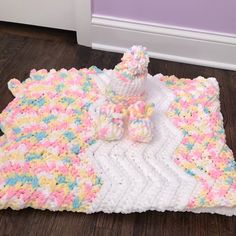 a crocheted blanket with a teddy bear sitting on it, next to a stuffed animal