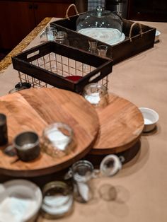 two wooden trays sitting on top of a table filled with plates and bowls next to a bottle