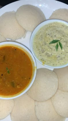 some food is on a white plate with sauces and pita bread as well