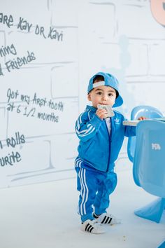 a young boy in blue is standing next to a toy airplane and holding a toothbrush