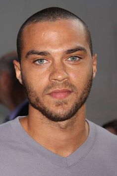 a close up of a person wearing a gray shirt and looking at the camera with an intense look on his face