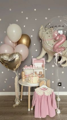 a baby's first birthday party with balloons, cake and other items on the table