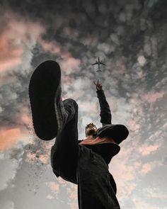 a man is reaching up into the air to catch a small airplane in the sky