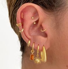 a woman wearing gold ear cuffs and earrings