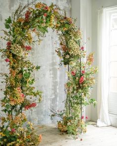 an arch made out of flowers in front of a window