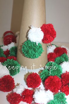 red, white and green pom - poms are scattered around a vase