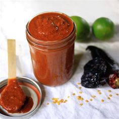 a jar filled with red sauce next to some fruit