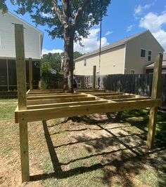 a wooden bench sitting in the middle of a yard next to a tree and fence